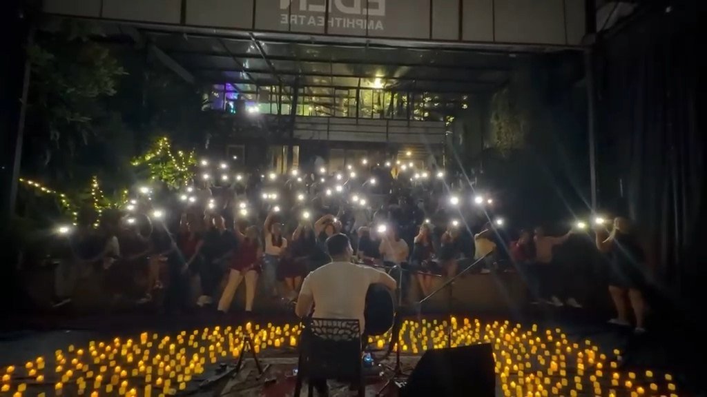 The crowd holding up phone lights above the candles as the set plays.