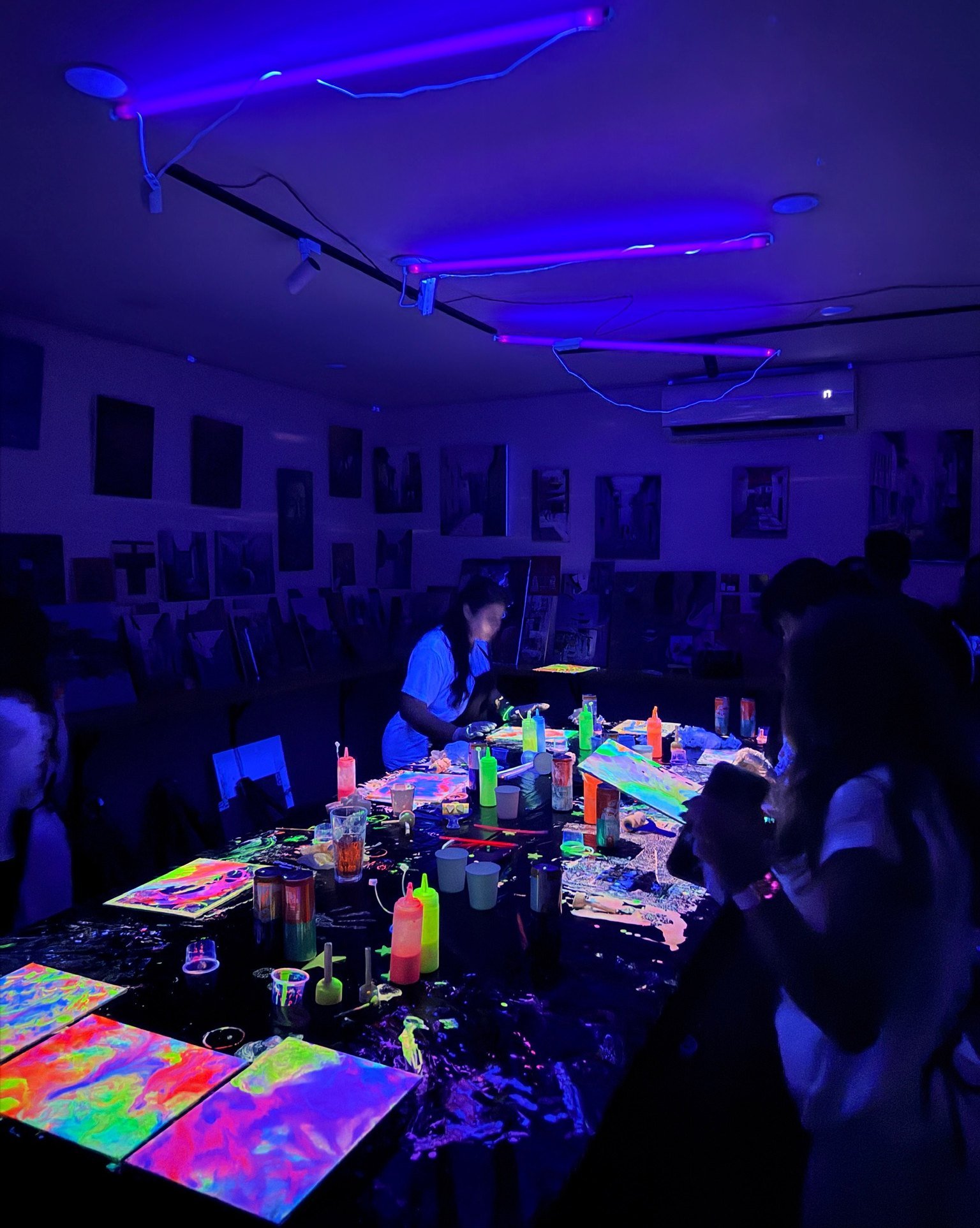 Guests painting with fluorescent colours around a UV-lit table.